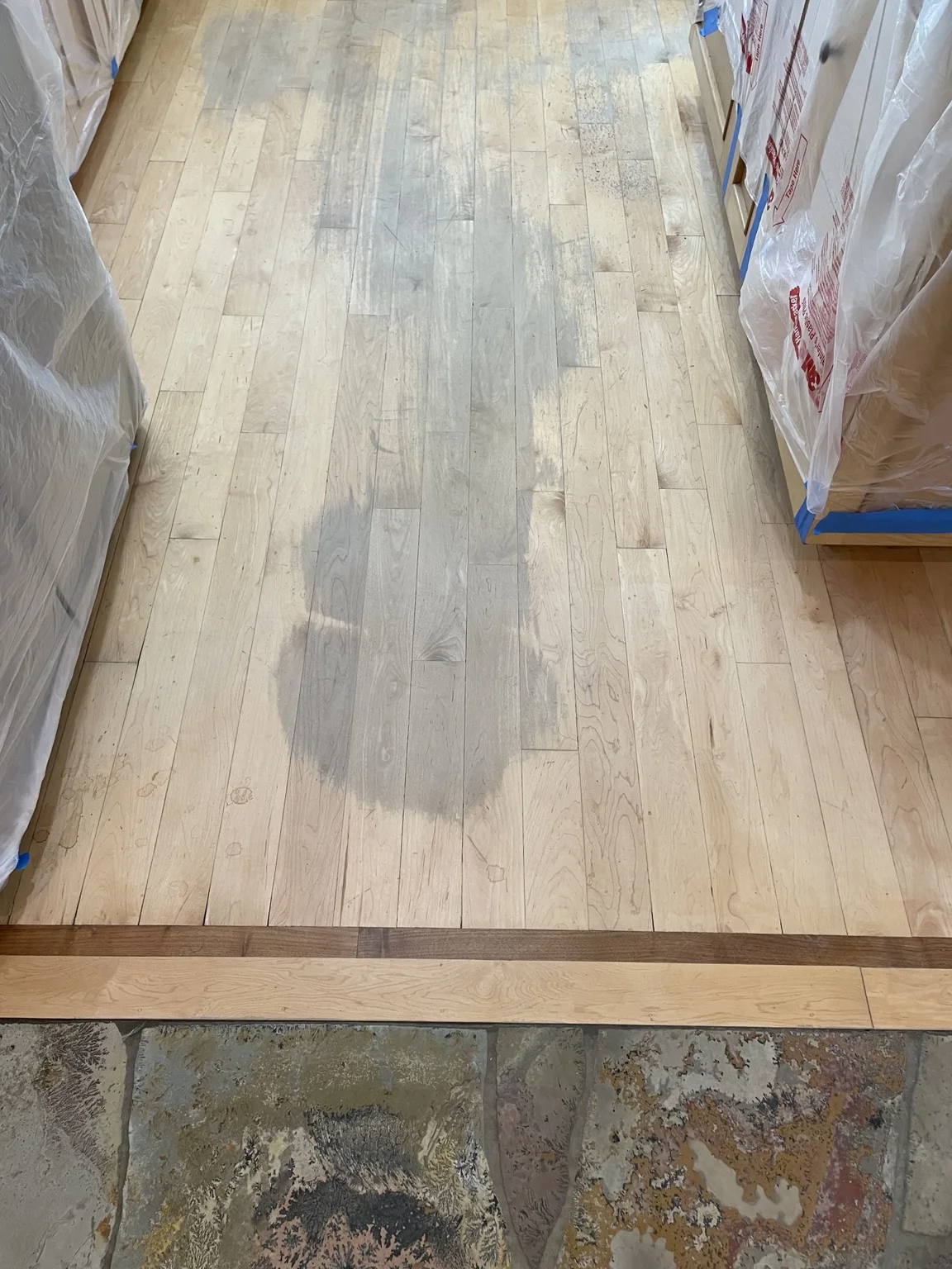 The same kitchen hardwood floor and dark border before refinishing, showing gray wear marks