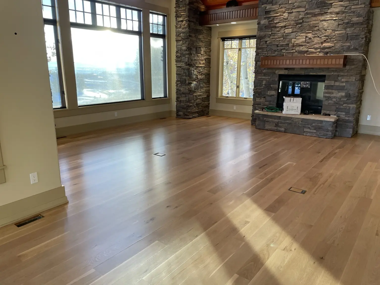 Light hardwood floor in a great room with stone fireplace