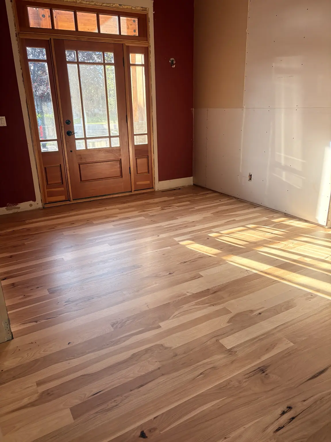 Sunlit natural hardwood flooring at a home entry