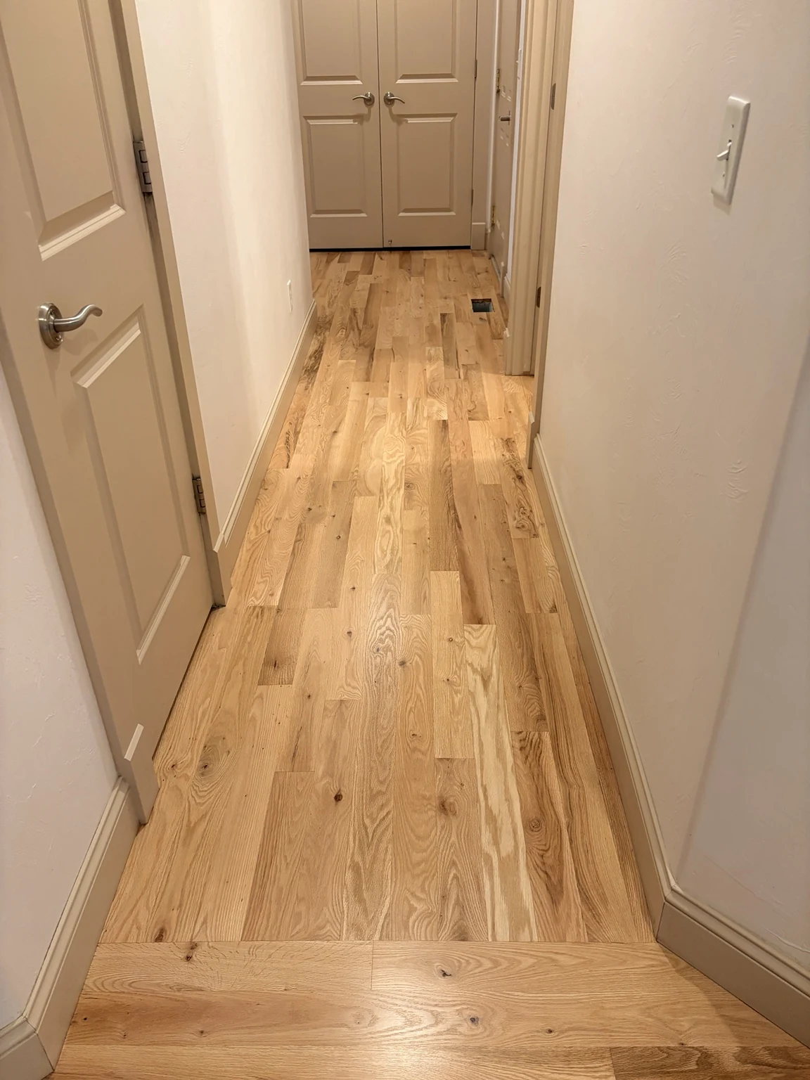 Finished hardwood hallway with a cross-board transition