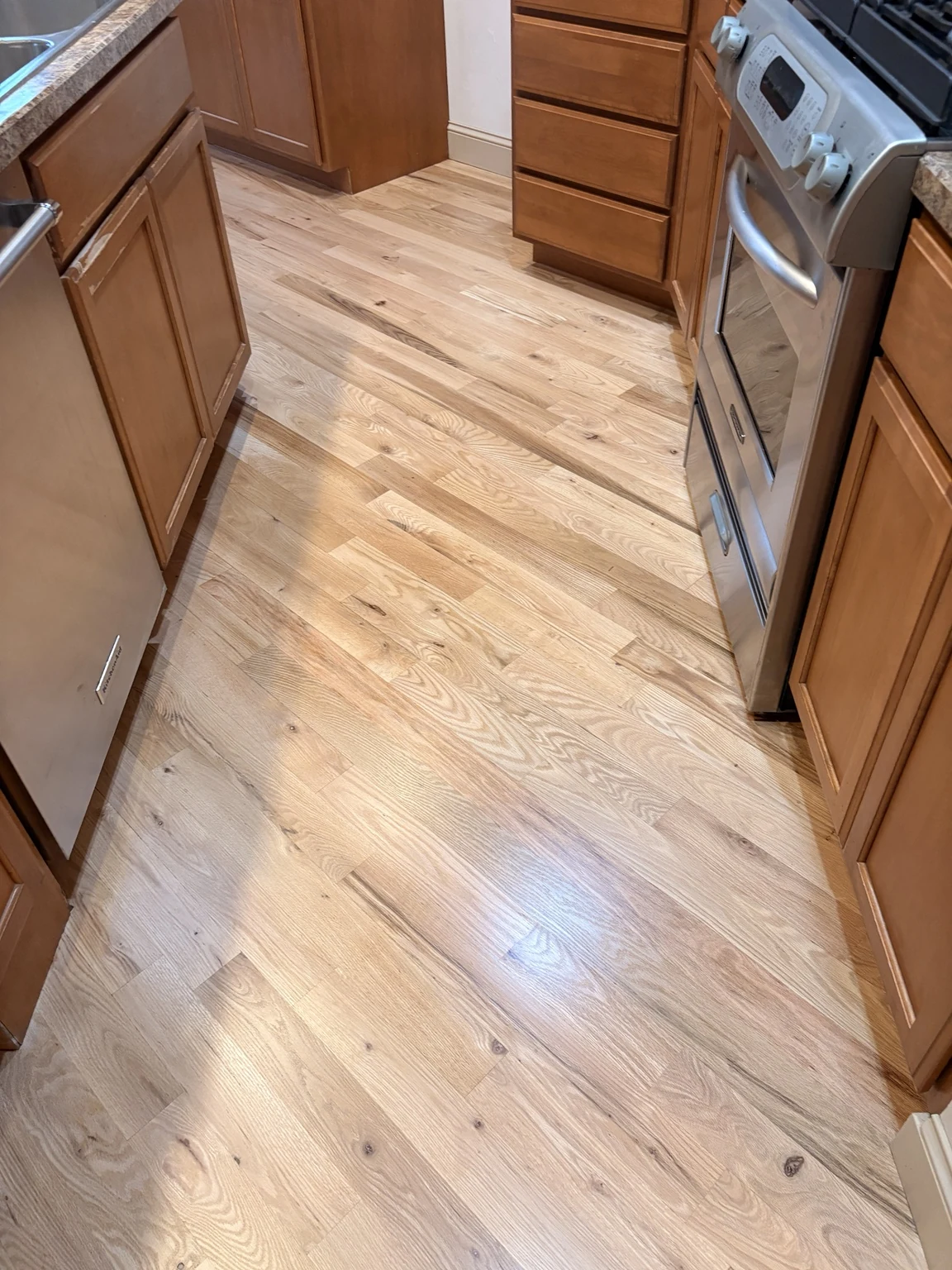 Natural hardwood kitchen floor around a range and cabinets