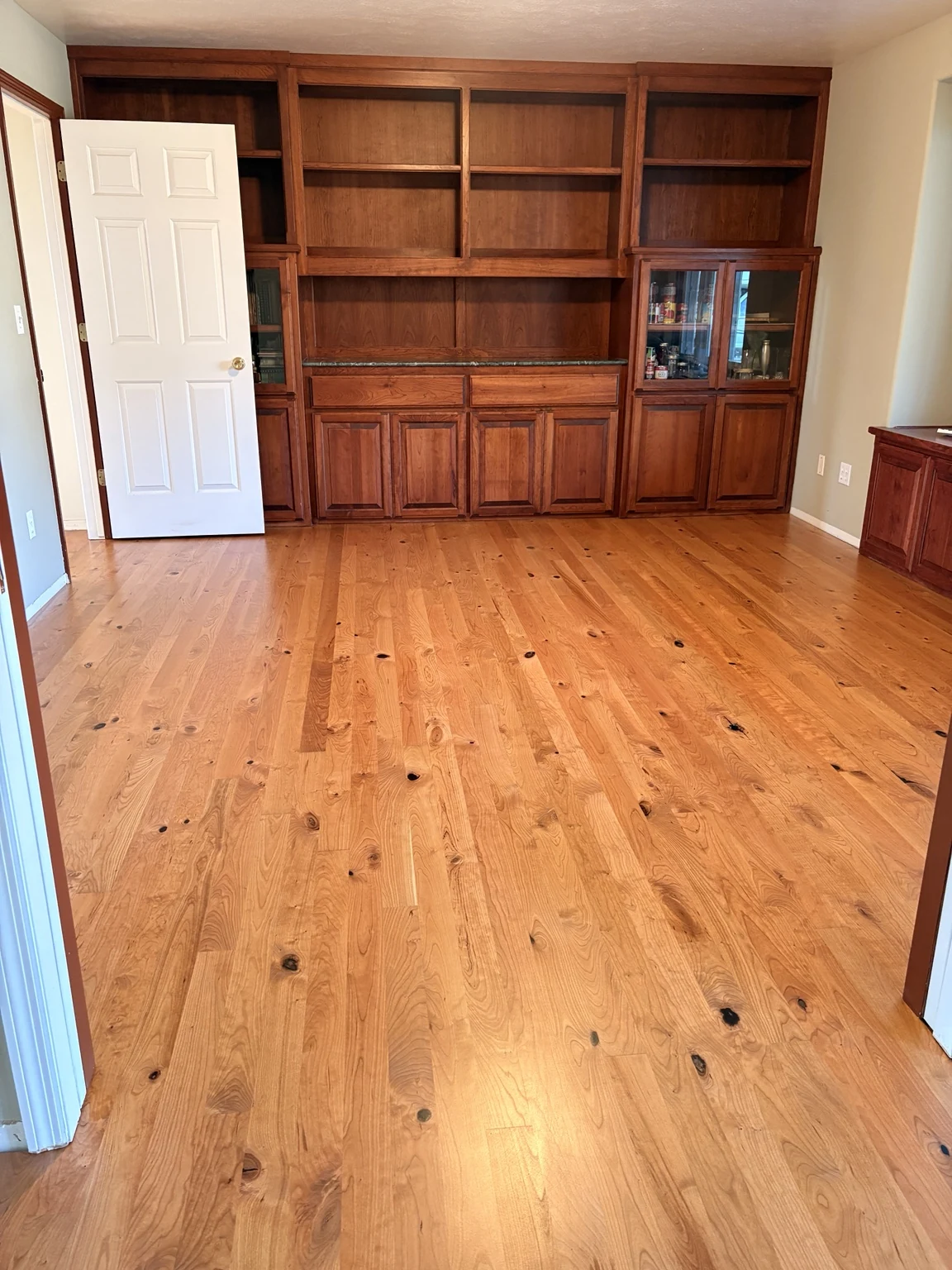 Character hardwood flooring in a room with built-in shelving